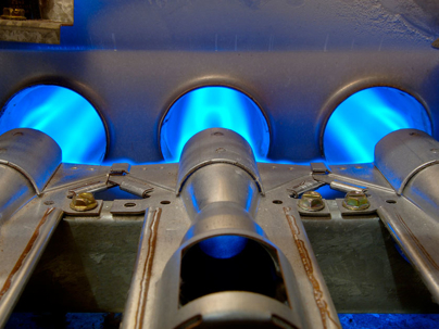 a gas furnace, specifically showing the burners with their characteristic blue flames.