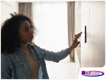 Woman adjusting a wall-mounted digital thermostat