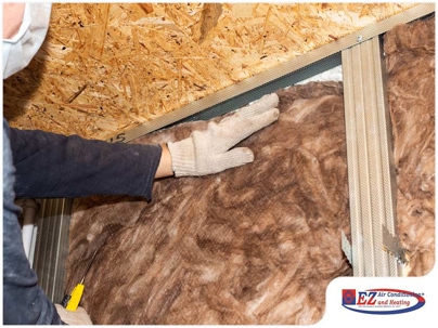person installing or adjusting fiberglass insulation