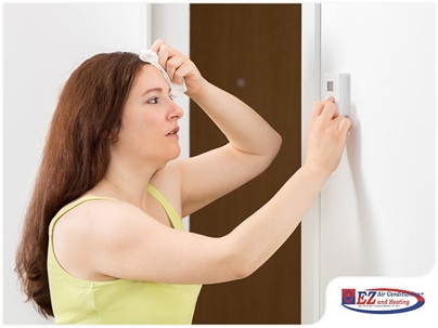 woman adjusting a wall-mounted digital thermostat