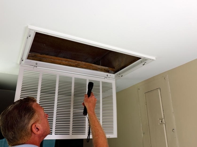 person inspecting an attic return air vent