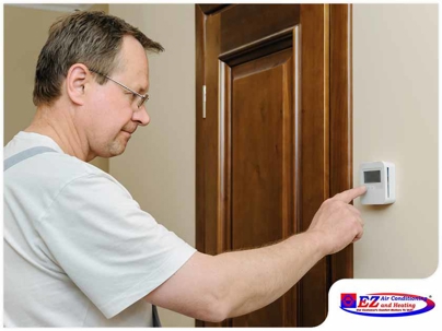 man adjusting a wall-mounted digital thermostat