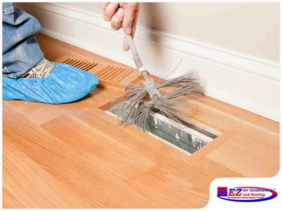 person cleaning a floor air vent (register)