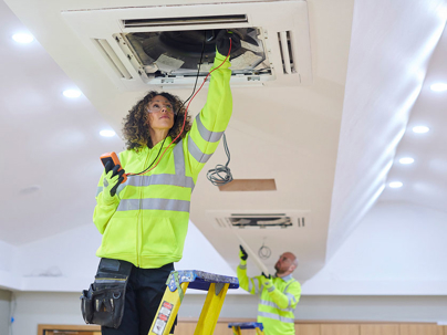 HVAC professionals, working on installing or maintaining an air conditioning system in a commercial or large residential building.