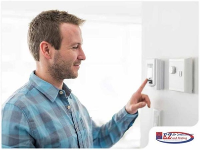 man adjusting a wall-mounted digital thermostat